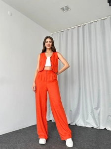 Detail von orangefarbenem ärmellosem Weste und weit geschnittener Hose mit Textur-Struktur