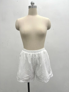 Detail shot of white lace hollow shorts featuring elastic waist and floral embroidery texture