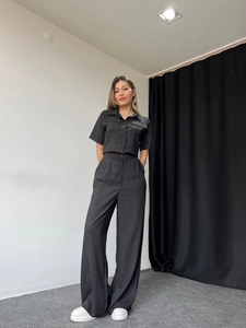 Close-up of black two-piece set featuring short-sleeve button top and high-waist wide-leg pants