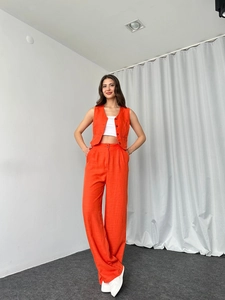 Detail einer leuchtend orangen Weste mit V-Ausschnitt und passender weiter Hose mit hohem Bund