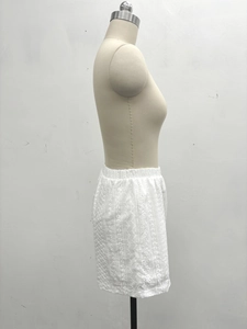 Detail of white cotton shorts with intricate floral embroidery and eyelet lace hem