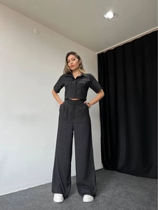 Close-up of black two-piece set featuring short-sleeved buttoned top and high-waist trousers