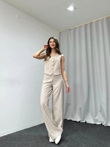 Detail view of the sleek low-saturation light oat-colored vest and wide-leg trousers set