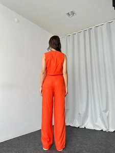 Rückansicht des leuchtend orangen Zweiteilers mit kurzem Top und weiten Hosenbeinen