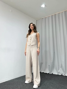Detail of beige vest set featuring five golden buttons and high-waisted wide-leg trousers