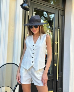 Détail d'un ensemble en lin blanc comprenant un gilet à col en V et un short taille haute