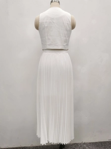 Detail eines weißen zweiteiligen Sets mit ärmellosem Crop-Top und langem Plissee-Rock