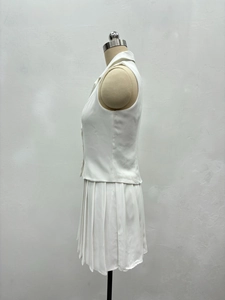 Détail d'un ensemble blanc avec haut sans manches à revers et jupe plissée sur mannequin