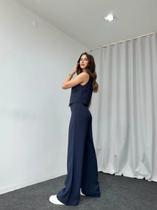 Side view of woman wearing deep blue two-piece set with sleeveless V-neck top and wide pants