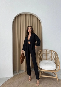 Detail of elegant black three-piece women's set with long cardigan and wide-leg trousers