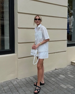 Detailed view of white eyelet embroidery on a short sleeve shirt and shorts set