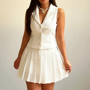 Détail d'un ensemble blanc deux pièces avec gilet sans manches et mini-jupe plissée chic