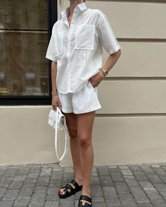 Detail of white two-piece set featuring hollow eyelet embroidery and shirt with chest pockets