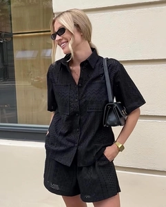 Detailed view of black eyelet embroidery on a short-sleeved shirt and matching shorts