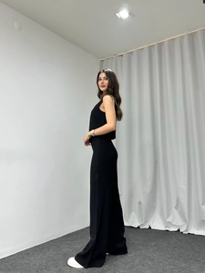 Detail view of women's black sleeveless top and trousers set with elegant drape fabric