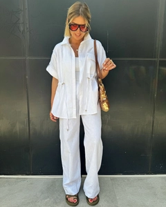 Full-body shot of a white linen two-piece set featuring a drawstring top and wide-leg pants
