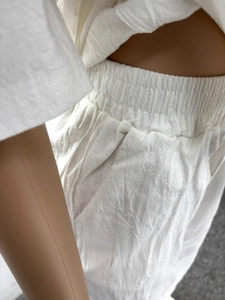 Detail of high-waisted elastic waistband and side pocket on white linen two-piece set