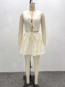 Détail du gilet blanc cassé avec nœuds et mini-jupe à bordure festonnée élégante