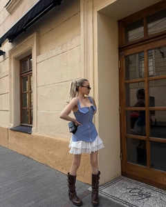 Street style shot of light blue zip-up vest paired with a white tiered ruffled mini skirt