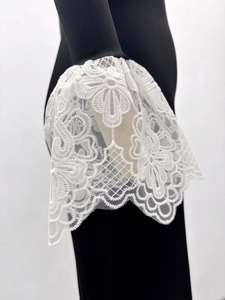 Détail des poignets en dentelle florale blanche avec broderie sur une robe noire chic