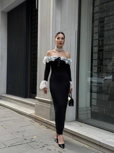 Détail de l'encolure dénudée avec bordure en dentelle blanche sur une robe longue noire