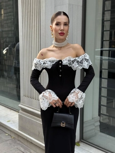 Détail d'une robe noire à épaules dénudées avec dentelle blanche et boutons perles