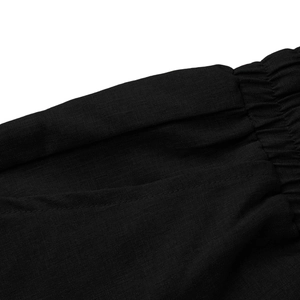 Dettaglio dei pantaloni a vita alta con coulisse elastica e trama del tessuto naturale