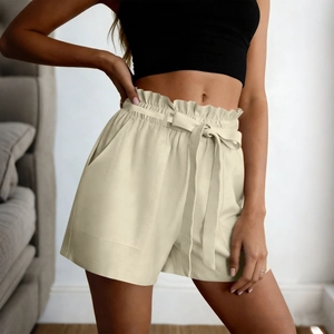 Detail of beige high-waisted shorts featuring elastic ruffled waist and drawstring bow