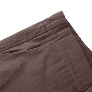 Detailed view of elastic waistband and side pocket on dark purple linen casual pants