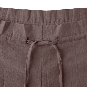 Detail of high waist drawstring on brown cotton linen wide leg trousers with textured fabric