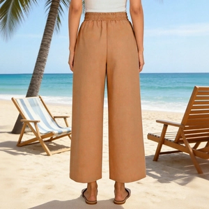 Dettaglio della vita alta con coulisse su pantaloni larghi in lino kaki in spiaggia