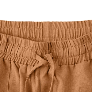 Dettaglio dei pantaloni in cotone caramello con vita elastica a coulisse e tessuto tramato