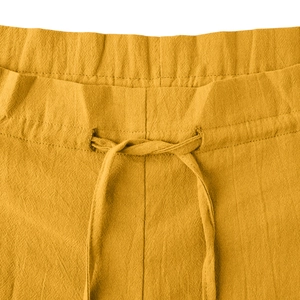 Detail of mustard yellow cotton linen trousers showing drawstring waist and fabric texture