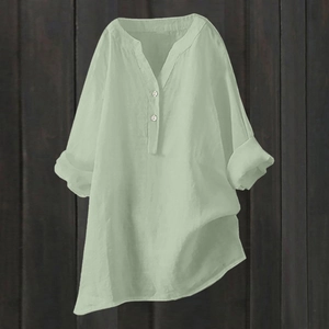Detailed close-up of light green linen V-neck shirt with irregular asymmetrical hemline