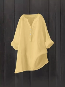 Relaxed fit women's V-neck linen shirt in bright yellow with rolled sleeves on wood background