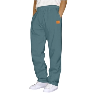 Detail of grey-blue sweatpants featuring a drawstring waist and orange square fabric patch