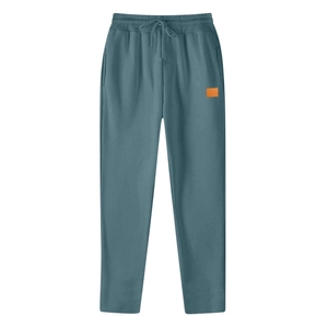 Detail view of elastic waistband with drawstring and orange patch on blue sports pants