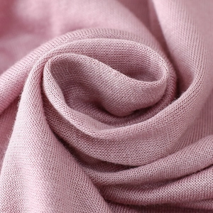 Macro shot of soft pink modal knit fabric showing smooth texture and elegant drape