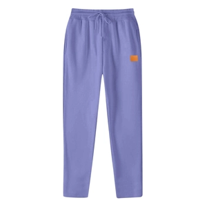 Detail of purple sweatpants featuring drawstring waist and orange decorative label