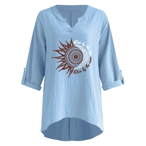 Detail of light blue V-neck linen shirt with sun and moon print and roll-up sleeves
