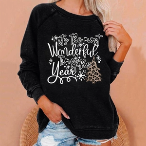 Detail of Christmas sweatshirt featuring leopard tree print and holiday typography