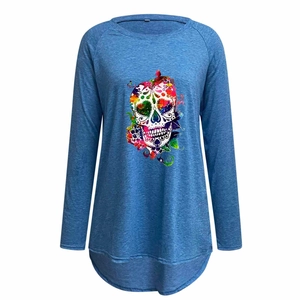 Detail of blue raglan sleeve shirt featuring a colorful sugar skull graphic and curved hem