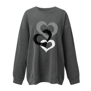 Detail of grey crewneck sweatshirt featuring a textured 3D heart pattern print on the chest