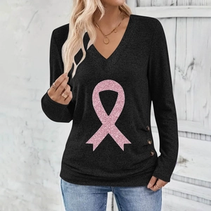 Detail of V-neck long sleeve top featuring pink glitter ribbon print and side buttons