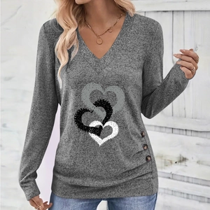 Close-up of V-neck top with interlocking heart print and button details on grey fabric