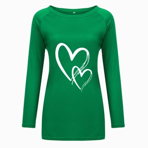 Détail d'un t-shirt vert à manches longues avec imprimé cœurs et étiquette de taille M