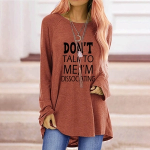 Détail d'un t-shirt à manches longues brique avec lettrage noir et ourlet arrondi
