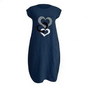 Détail d'imprimés cœurs entrelacés et poche sur une robe midi en lin bleu foncé