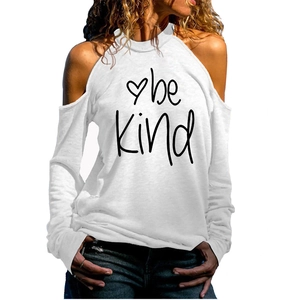 Détail de l'épaule dénudée et de l'imprimé cœur 'be Kind' sur ce haut blanc à manches longues