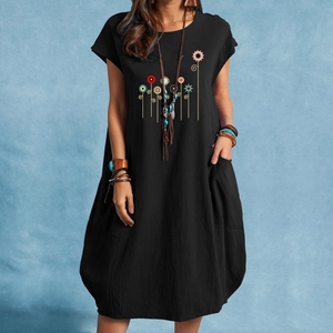 Detail of loose-fit black cotton linen dress featuring colorful floral print and side pockets